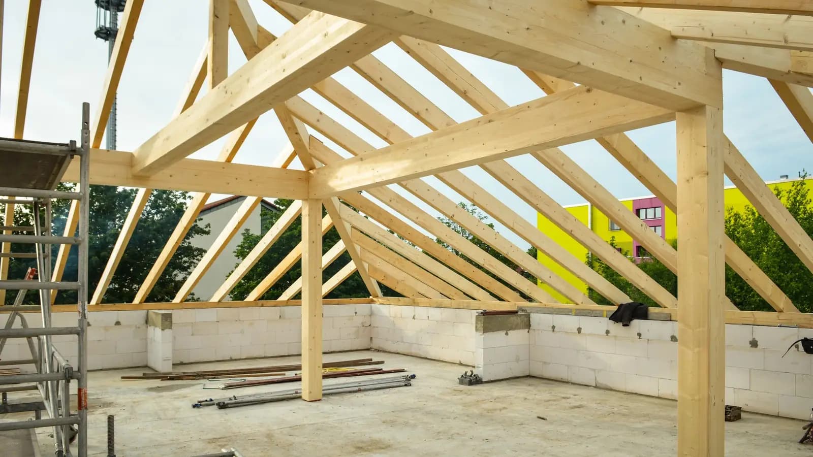 New house under construction showing exposed wood roof trusses and framing against a clear sky