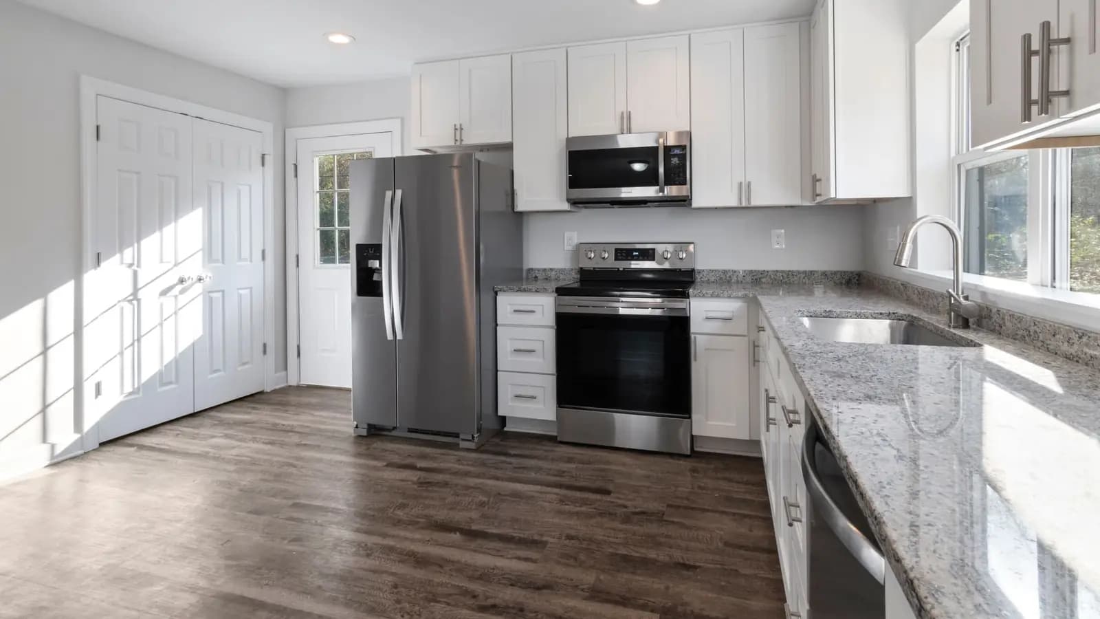 Renovated kitchen with white shaker cabinets, stainless appliances, and hardwood floors